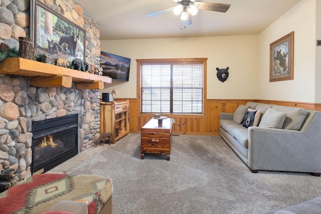 living room with a fireplace, wood walls, ceiling fan, and carpet flooring