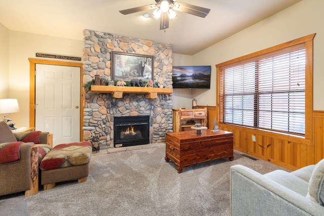 living room with ceiling fan, wooden walls, a fireplace, and carpet flooring