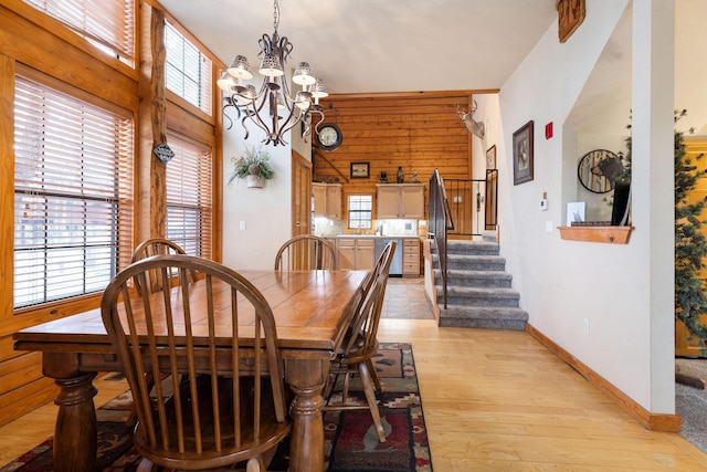 dining area featuring a notable chandelier, light hardwood / wood-style floors, and a high ceiling