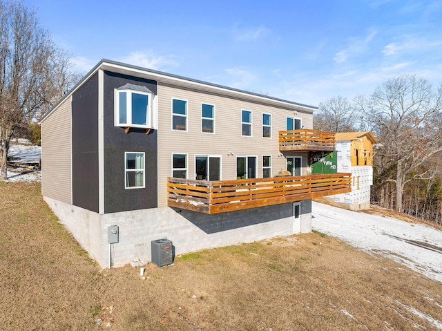 rear view of house featuring a wooden deck, cooling unit, and a yard