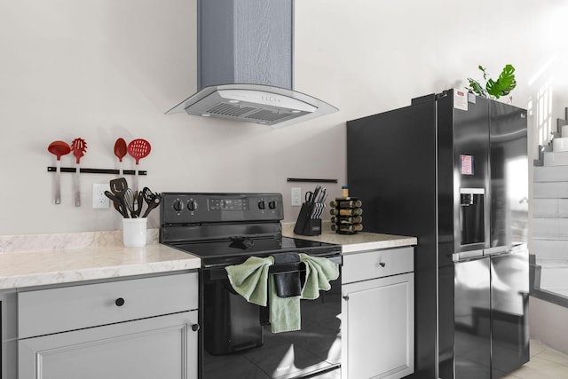 kitchen featuring black appliances, wall chimney range hood, gray cabinetry, and light tile patterned flooring