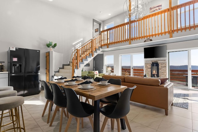 tiled dining space featuring a high ceiling, a chandelier, and plenty of natural light