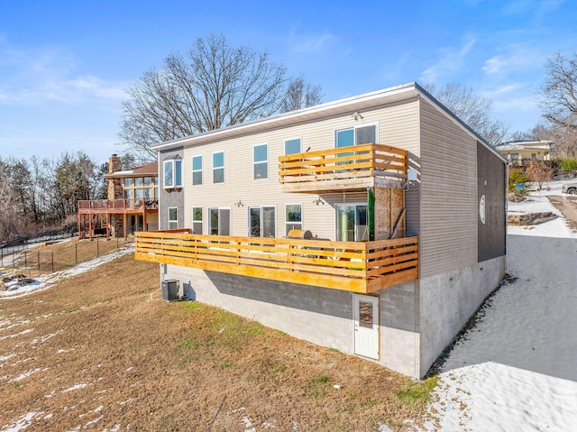 view of front of house with central AC unit, a front lawn, and a balcony