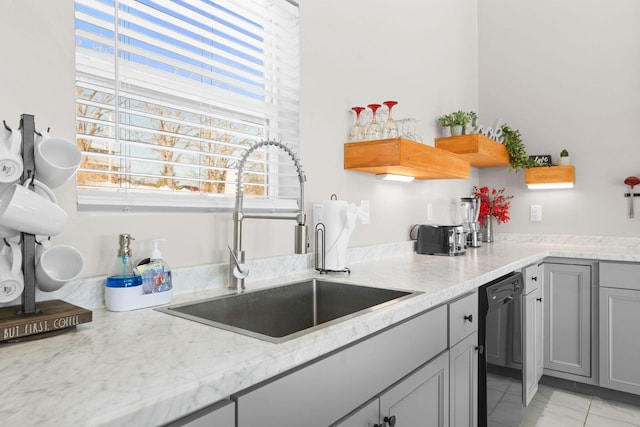 kitchen with dishwasher, gray cabinets, sink, light tile patterned flooring, and light stone countertops