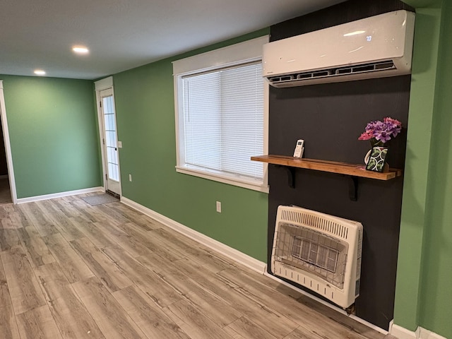 interior space with a wall mounted AC, heating unit, and light hardwood / wood-style flooring