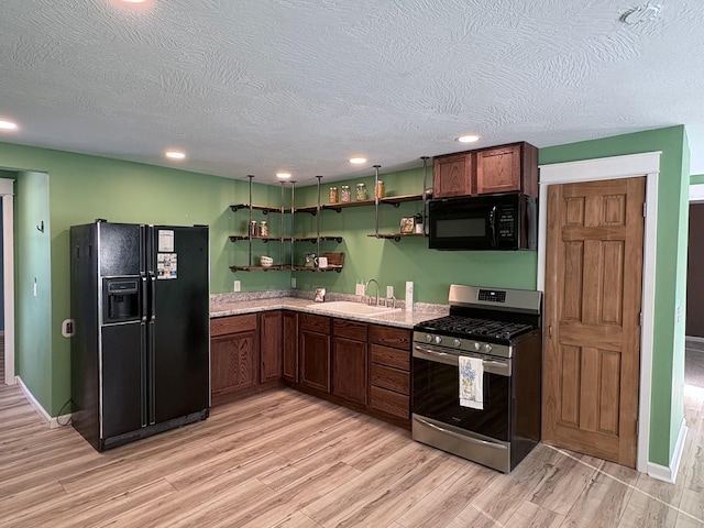 kitchen with light wood-type flooring, a textured ceiling, sink, and black appliances