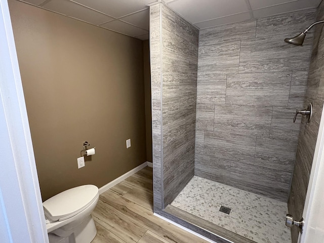 bathroom featuring toilet, wood-type flooring, and tiled shower