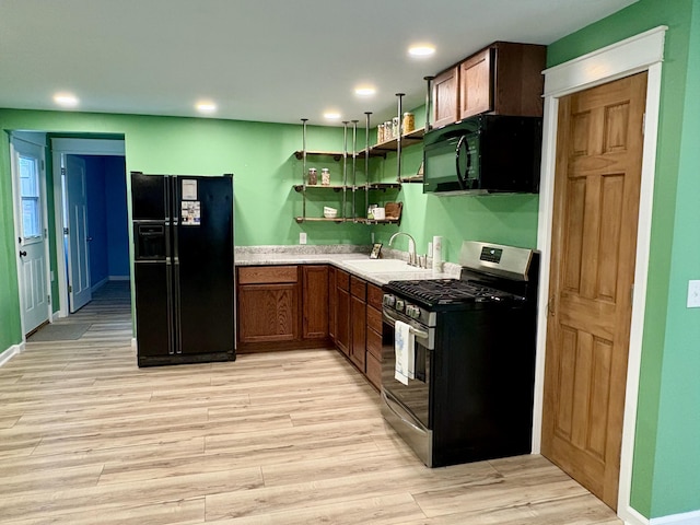 kitchen featuring black appliances, sink, and light hardwood / wood-style flooring