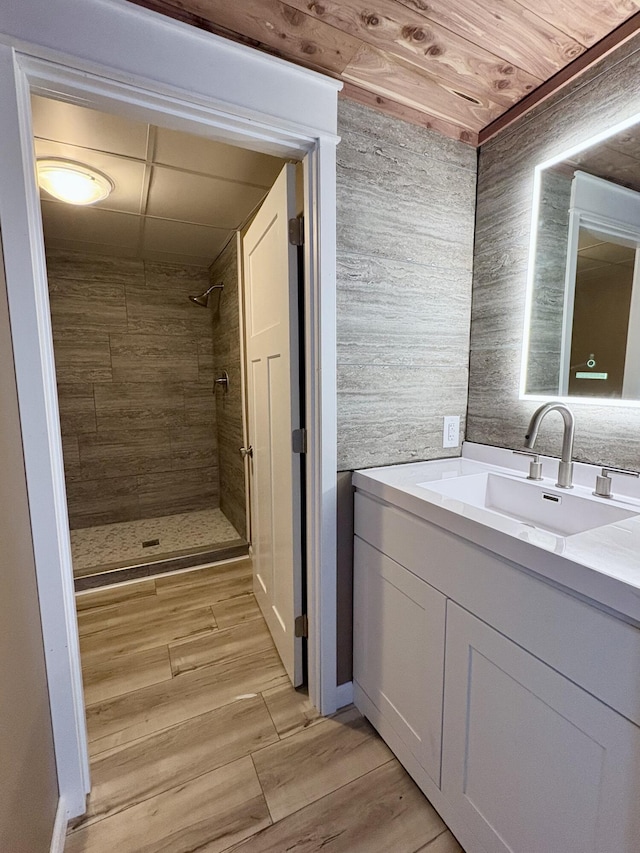 bathroom featuring vanity, a tile shower, and wood ceiling