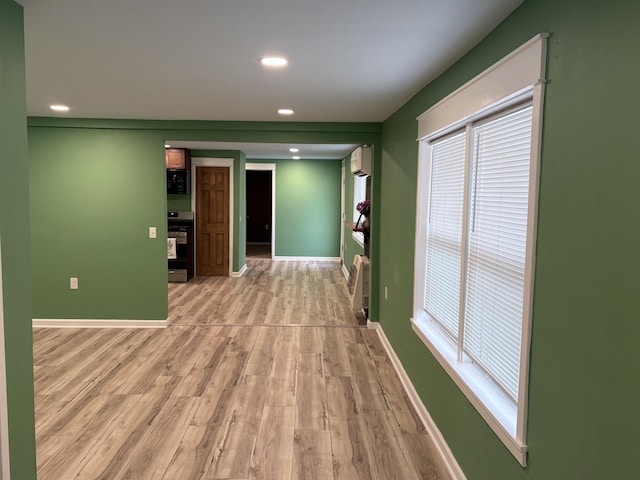 hall with a wall unit AC and light wood-type flooring