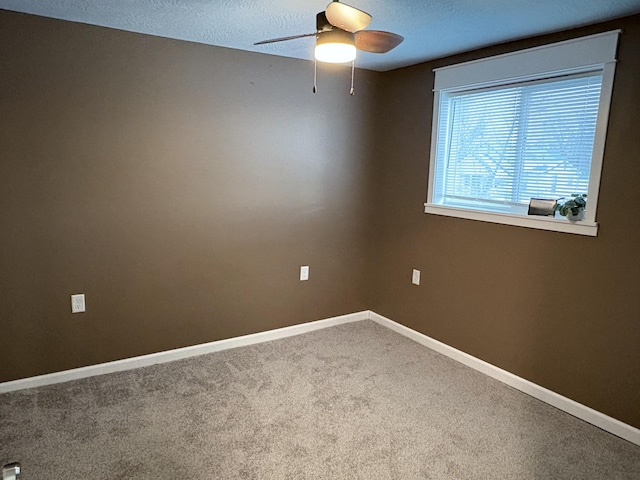 carpeted spare room with a textured ceiling and ceiling fan