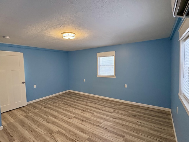 empty room with light hardwood / wood-style floors and a textured ceiling