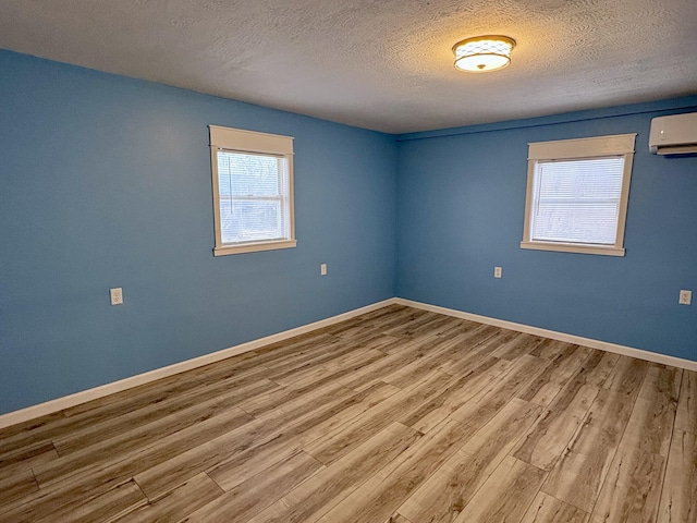 empty room featuring an AC wall unit, a textured ceiling, and wood-type flooring