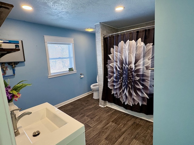 bathroom featuring toilet, a shower with shower curtain, wood-type flooring, a textured ceiling, and sink