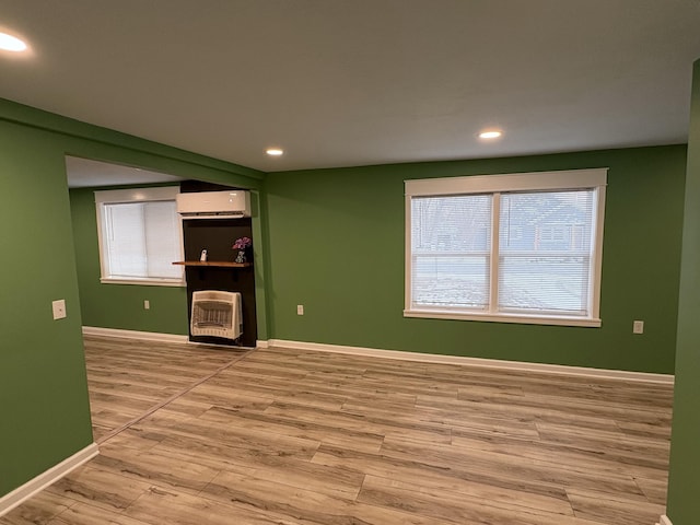 unfurnished living room with a wealth of natural light, hardwood / wood-style flooring, and an AC wall unit