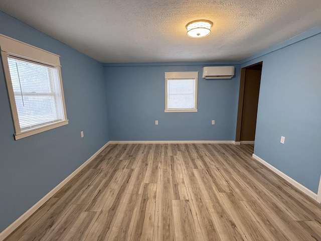 spare room with hardwood / wood-style flooring, a textured ceiling, and a wall unit AC