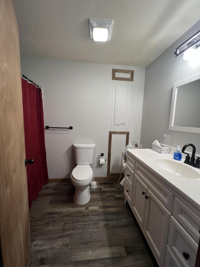 bathroom with toilet, vanity, wood-type flooring, and a textured ceiling