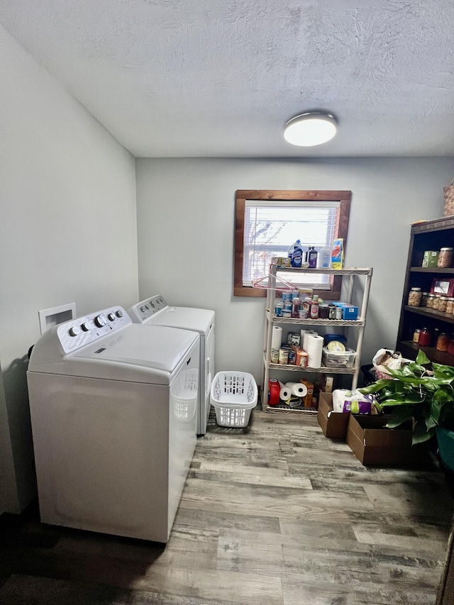 laundry room featuring a textured ceiling, washer and clothes dryer, and light hardwood / wood-style flooring