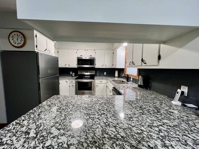 kitchen featuring dark stone countertops, sink, stainless steel appliances, and white cabinets