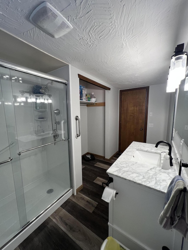 bathroom with hardwood / wood-style flooring, a textured ceiling, vanity, and a shower with door