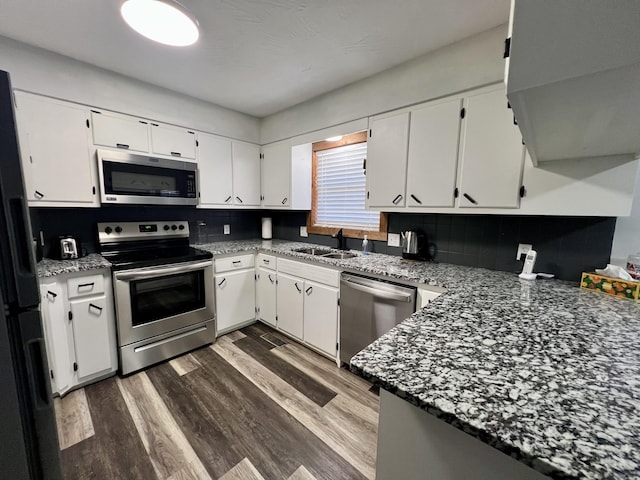 kitchen with stainless steel appliances, white cabinets, stone counters, sink, and dark hardwood / wood-style floors