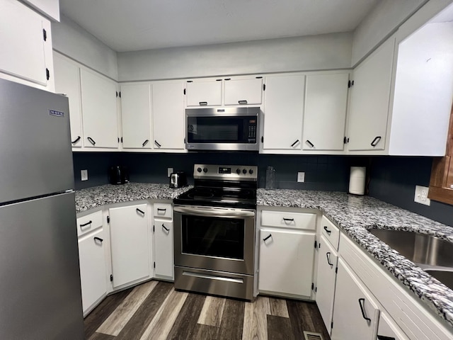 kitchen featuring white cabinetry, dark wood-type flooring, appliances with stainless steel finishes, and tasteful backsplash