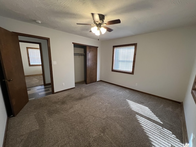 unfurnished bedroom with ceiling fan, dark colored carpet, a textured ceiling, and a closet