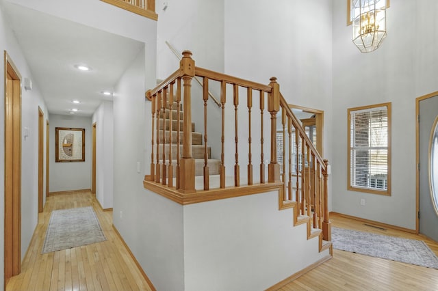 entryway with a high ceiling, an inviting chandelier, and light hardwood / wood-style flooring