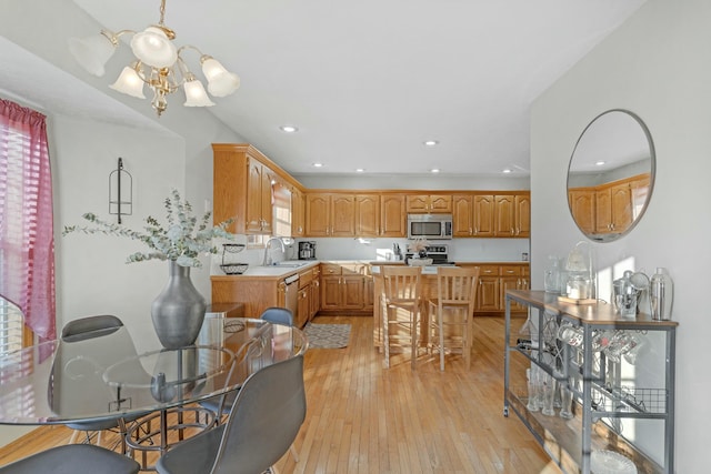 dining area featuring light wood-type flooring, a notable chandelier, and sink