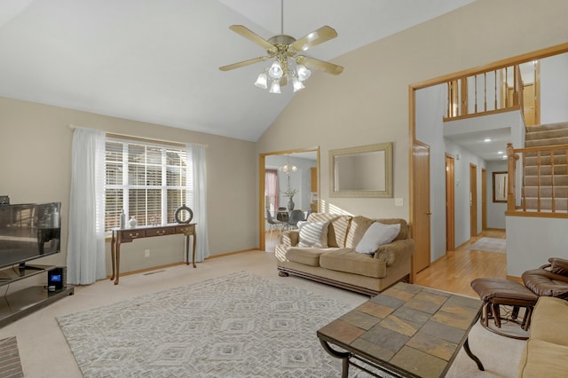 living room featuring ceiling fan with notable chandelier, high vaulted ceiling, and light carpet