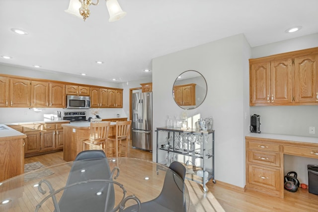 kitchen with appliances with stainless steel finishes, light hardwood / wood-style floors, and a kitchen island