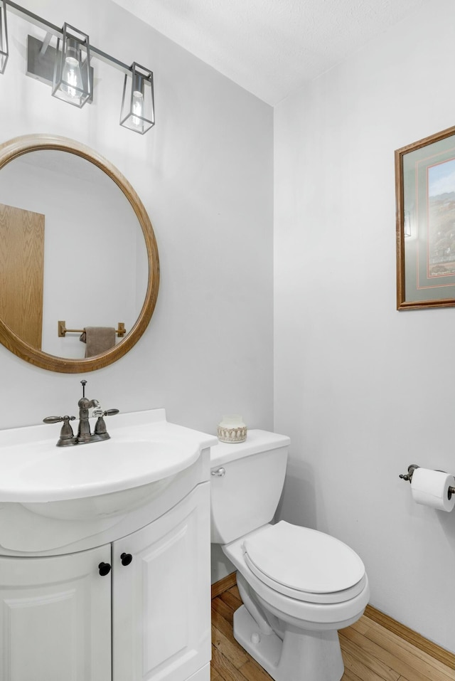 bathroom with hardwood / wood-style flooring, a textured ceiling, toilet, and vanity