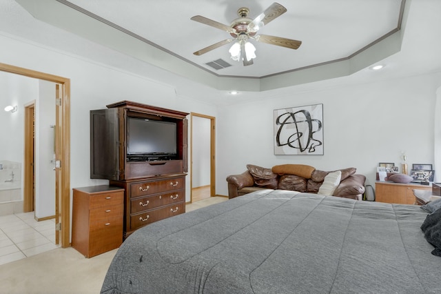 bedroom with light tile patterned floors, ceiling fan, a tray ceiling, ensuite bath, and ornamental molding