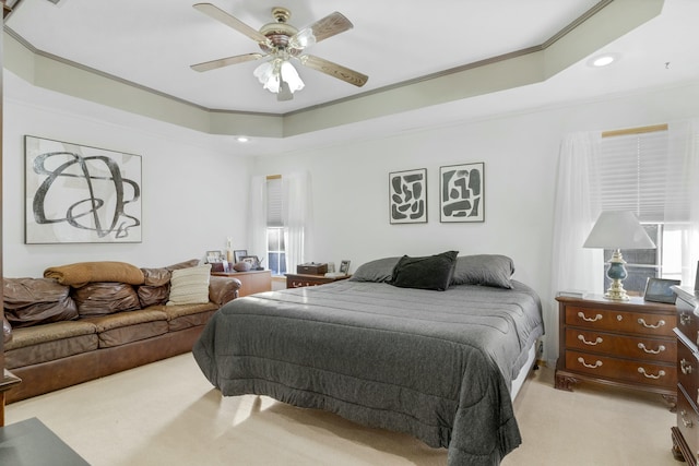 bedroom featuring ceiling fan, a tray ceiling, crown molding, and light carpet