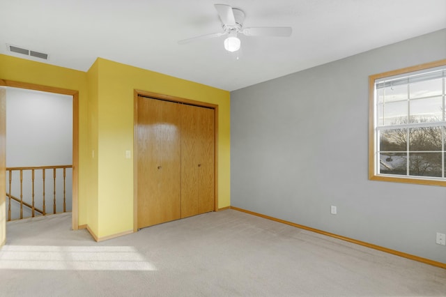 unfurnished bedroom with ceiling fan, a closet, and light carpet