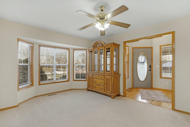 foyer entrance with light carpet and ceiling fan