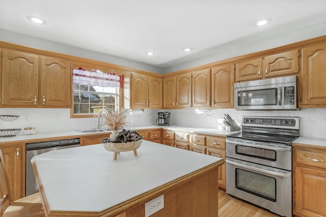 kitchen featuring backsplash, a kitchen island, sink, light hardwood / wood-style flooring, and appliances with stainless steel finishes