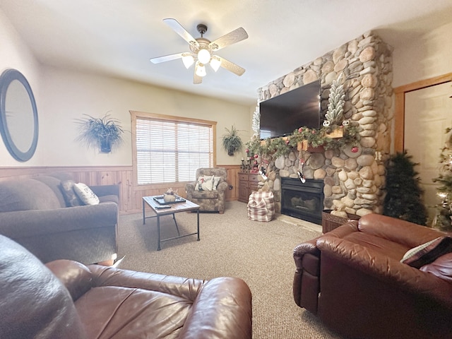 carpeted living room featuring ceiling fan, a wood stove, and wooden walls