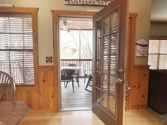 doorway with french doors, ceiling fan, light hardwood / wood-style flooring, and wood walls