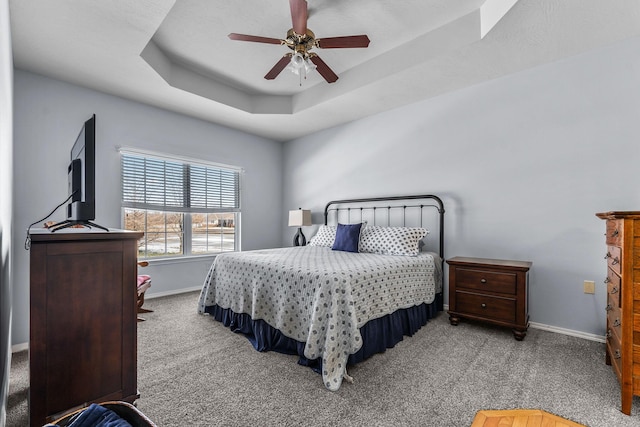 carpeted bedroom featuring ceiling fan and a raised ceiling