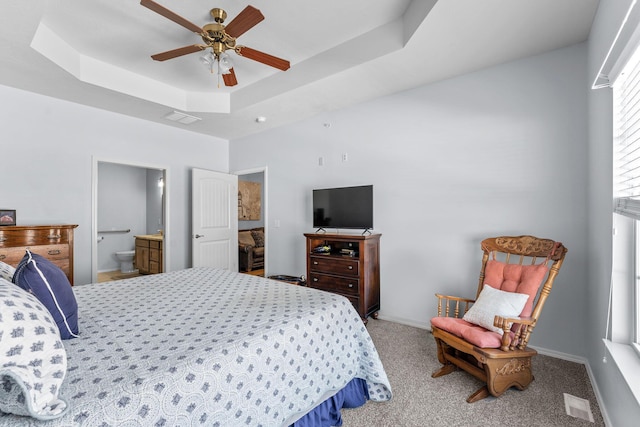 carpeted bedroom with ceiling fan, connected bathroom, and a raised ceiling