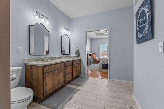 bathroom with toilet, vanity, ceiling fan, and tile patterned floors