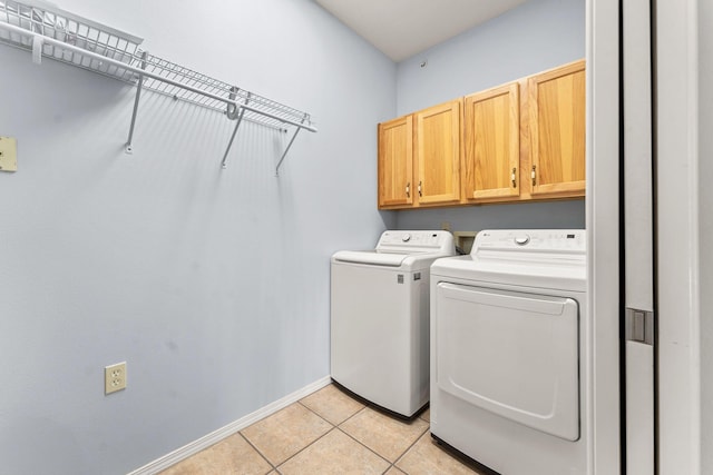 laundry room with cabinets, light tile patterned flooring, and washer and clothes dryer