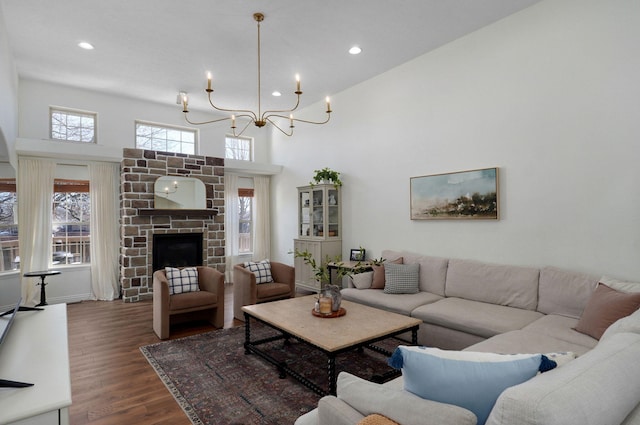 living room with a towering ceiling, dark hardwood / wood-style flooring, a chandelier, and a fireplace