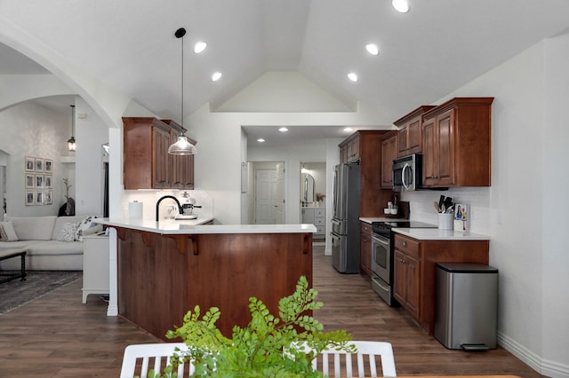 kitchen featuring hanging light fixtures, appliances with stainless steel finishes, kitchen peninsula, and tasteful backsplash