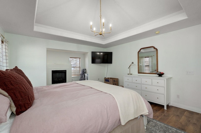 bedroom with a raised ceiling, dark hardwood / wood-style floors, and a notable chandelier