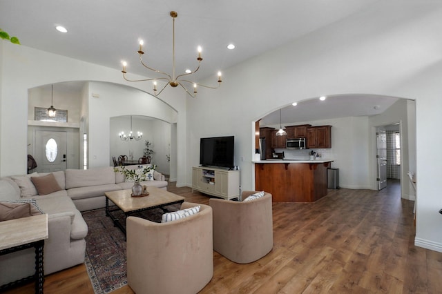 living room featuring an inviting chandelier, a towering ceiling, and hardwood / wood-style floors