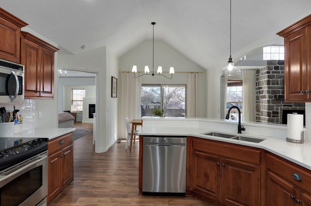 kitchen featuring a stone fireplace, appliances with stainless steel finishes, backsplash, a chandelier, and sink