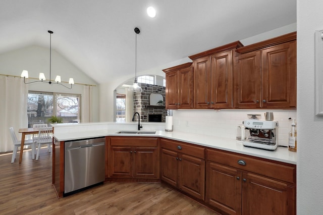 kitchen featuring kitchen peninsula, decorative backsplash, pendant lighting, stainless steel dishwasher, and sink