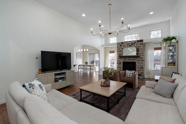 living room featuring a brick fireplace, a high ceiling, dark hardwood / wood-style floors, and a notable chandelier